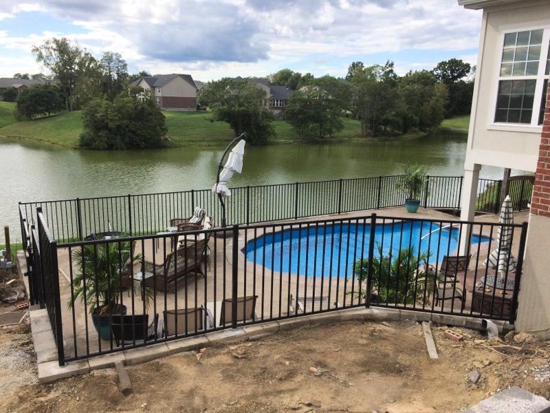 Black aluminum pool fence enclosing a lakefront backyard pool in Kentucky, ensuring safety and legal compliance with state pool barrier regulations by R&M Fence.