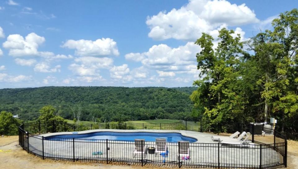 Secure hillside pool with a metal safety fence, showing residential pool fence rules and pool barrier regulations in Kentucky.