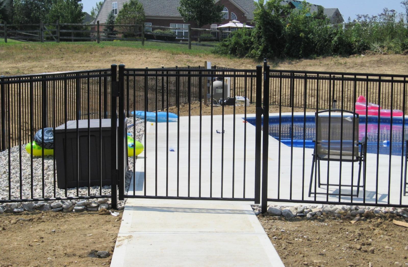 Black metal pool safety fence with a self-latching gate enclosing a residential pool in Kentucky, demonstrating compliance with state pool barrier regulations by R&M Fence.
