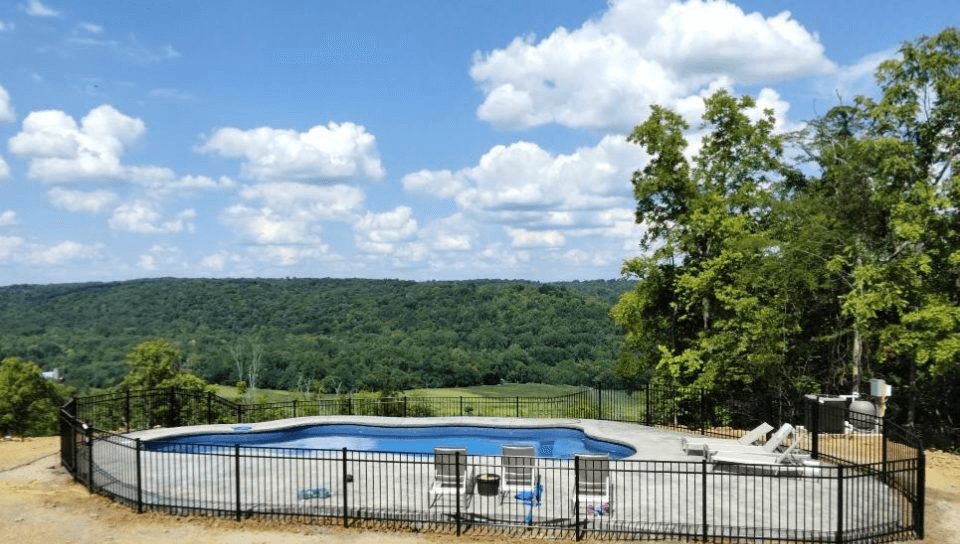 Black metal pool safety fence installed on a sloped Kentucky backyard overlooking hills