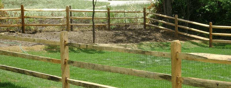 Long run of split rail fence marking a residential property line with open sightlines