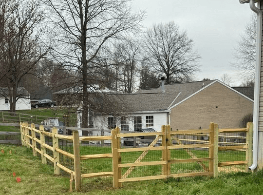 Three-rail split rail fence with matching wood gate on a suburban lot