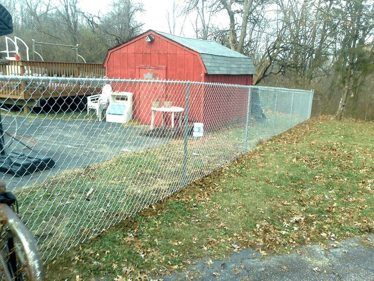 Chain link backyard fence installed along a sloped yard near a shed