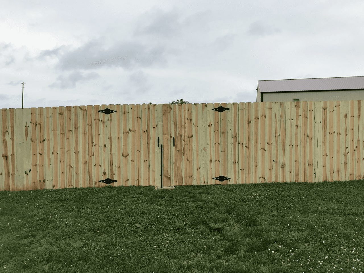 Stepped wood privacy fence installed on a sloped backyard