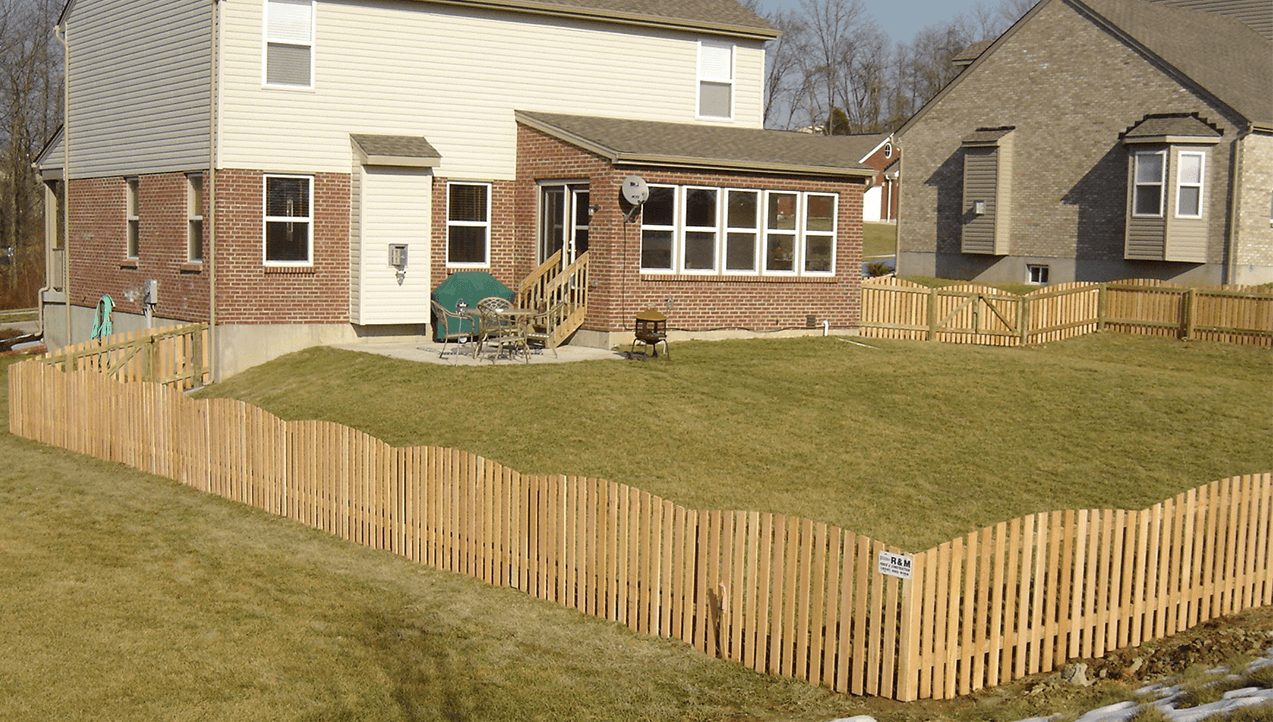 Wood privacy fence enclosing suburban backyard on sloped lawn 